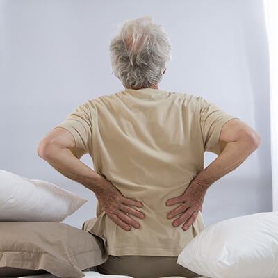 man sitting on bed with back pain