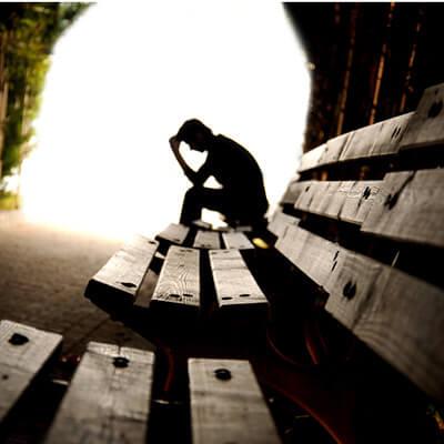 man sitting on a bench park looking depressed